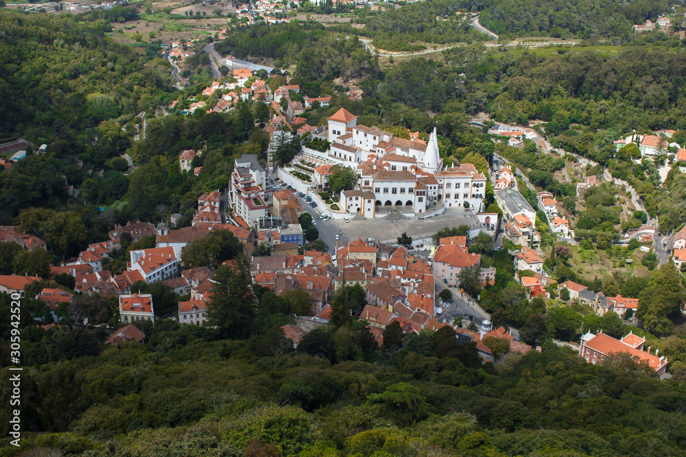 View from the fortress wall of the castle of the Moors. View of the small town of Sintra near Lisbon. Top view of a cozy village with red roofs in the middle of a green valley and forest.