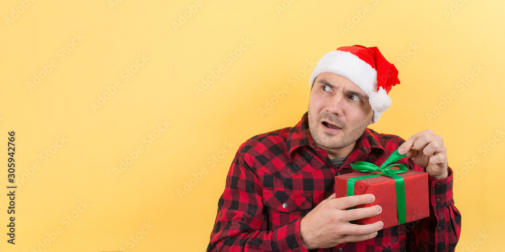 A thief in a red hat, stole someone else's Christmas gifts. Angry character, negative human emotions. Yellow background, copy space. A thief in a red hat, stole someone else's Christmas gifts. Angry character, negative human emotions. Yellow background, copy space.