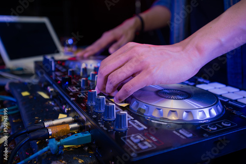 Sound engineer on mixer, close up of DJ hands on stage mixing, disc jockey and mix tracks on sound mixer controller, playing music at bar, disco tech or night club party. 