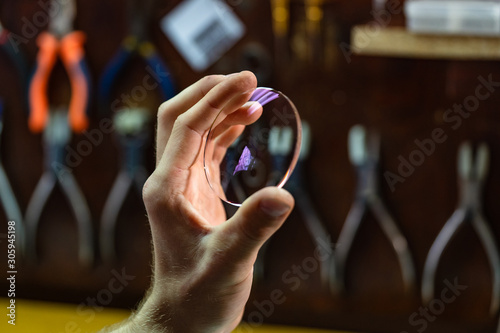 ophthalmologist hands close up, showing a glass lens for spectacles. Blurred background. Ophtalmologist equipment. Vision correction concept. photo