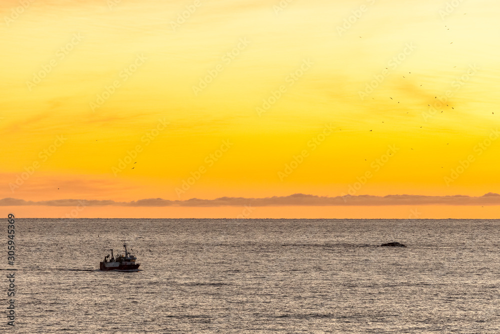 fishing boat with amazing sunset in background in lofoten, norway.