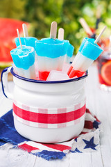 Red-white-and-blue popsicles on an outdoor table with summer drinks