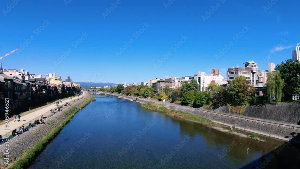 A beautiful high angle shot of Kamo River at Kyoto, Japan during Autumn on top of Shijo bridge with people walking beside the riverbank. A beautiful high angle shot of Kamo River at Kyoto, Japan during Autumn on top of Shijo bridge with people walking beside the riverbank.