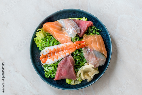 Sashimi Salad with Wakame, Seaweed, Salmon, Sea Bass, Shrimp, Kani, Mackerel Fish, Tuna served with Chopsticks.