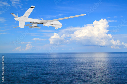 unmanned RC military drone flies over calm sea with beautiful white clouds on blue sky