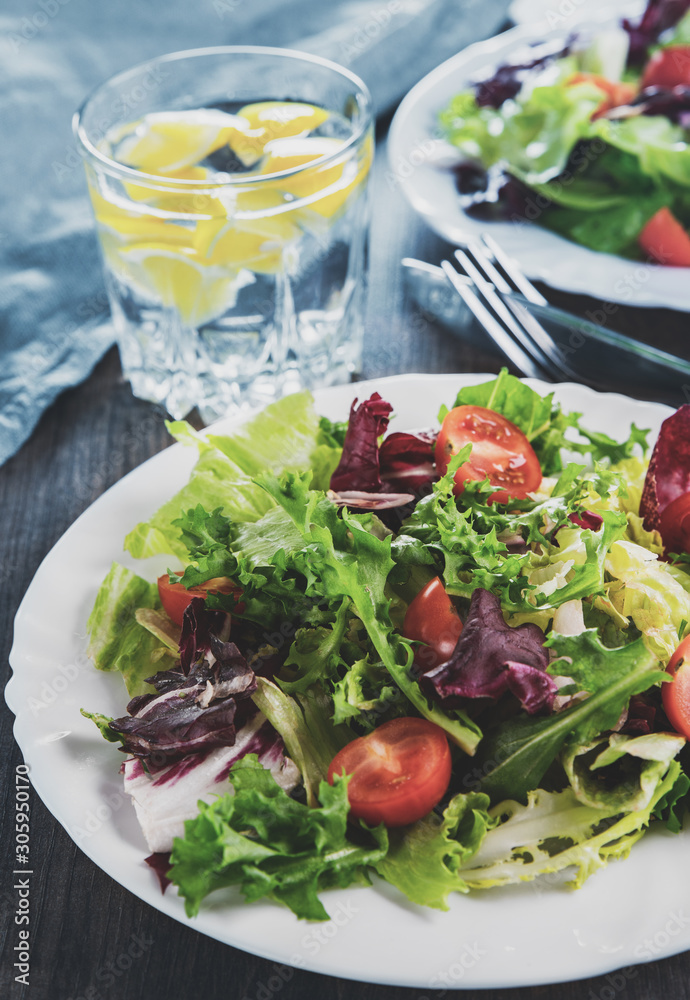 various fresh mix salad leaves with tomato in white plate on wooden background various fresh mix salad leaves with tomato in white plate on wooden background