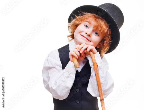 kid actor in the theatre, stylish boy in hat isolated on white background, happy child actor with a cane in his hand dressed in a black suit, talented red curly boy playing in the theatre