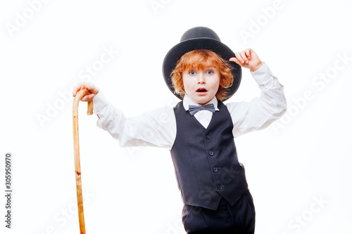 kid actor in the theatre, stylish boy in hat isolated on white background, happy child actor with a cane in his hand dressed in a black suit, talented red curly boy playing in the theatre