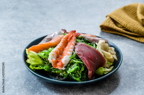 Sashimi Salad with Wakame, Seaweed, Salmon, Sea Bass, Shrimp, Kani, Mackerel Fish, Tuna served with Chopsticks. photo