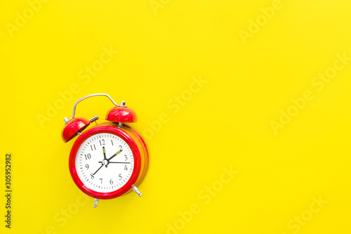 Red vintage alarm clock on a yellow background