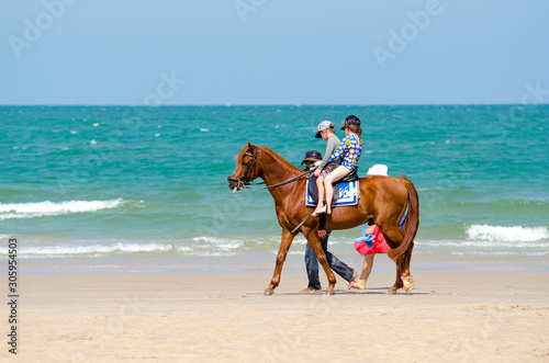 Children riding horses, walking on the beach