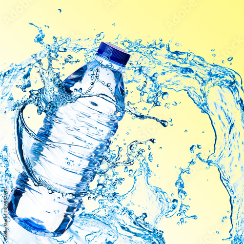 Splashes of water around a plastic bottle on a light background. Drinking clear water.
