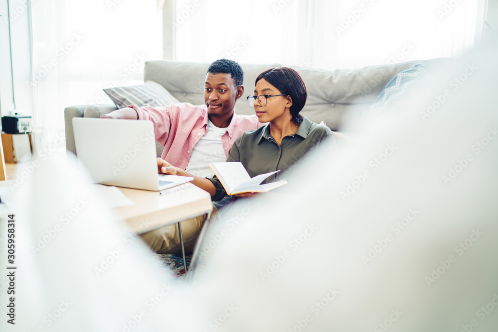 Positive african american couple making shopping on laptop computer browse web page at home interior , positive dark skinned family making video call using application on netbook at apartment. Positive african american couple making shopping on laptop computer browse web page at home interior , positive dark skinned family making video call using application on netbook at apartment.