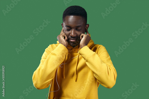 young black man in yellow hoodie listens to music