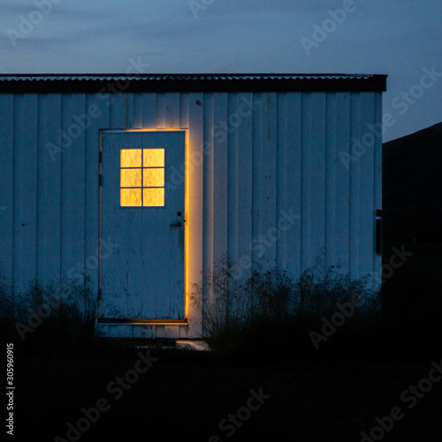 Photos Mysterious creepy ajar door at night, with yellow light through window