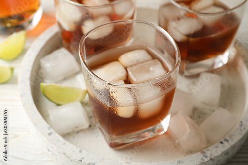 Marble tray with glasses of whiskey and lime on white background, close up