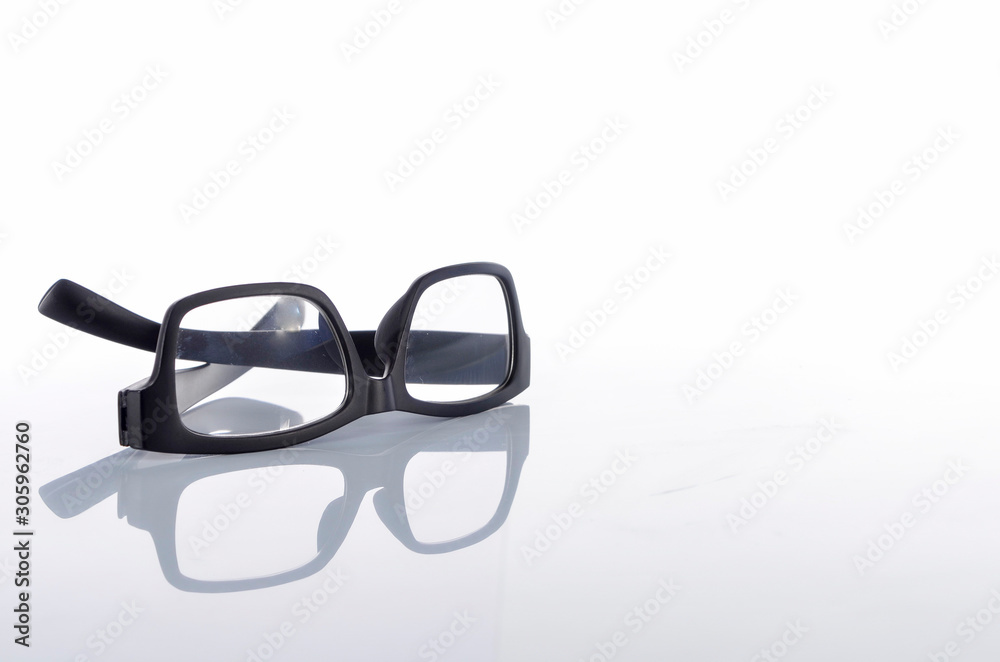 View of black frame spectacles glasses in a white background. Selective focus. View of black frame spectacles glasses in a white background. Selective focus.