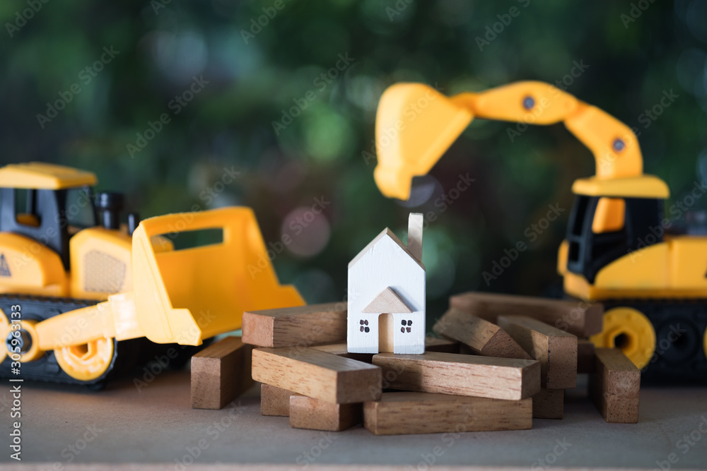 Yellow excavator and bulldozer models with home model on wood block. Yellow excavator and bulldozer models with home model on wood block.