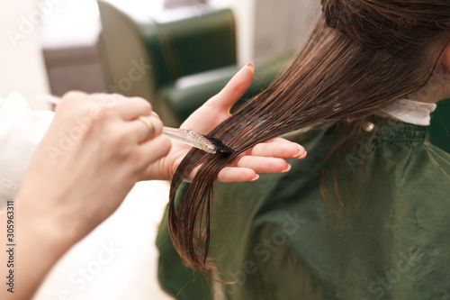 Hairdresser applies a hair mask to the woman in the beauty salon. Botox and keratin hair straightening procedure