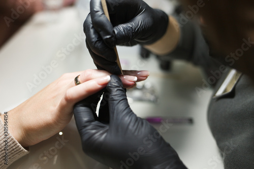 Manicurist cleans a client’s cuticle with a orange stick