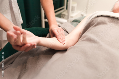 Doctor cosmetologist massages the hands of his patient. Client of a beauty salon enjoys a hand massage