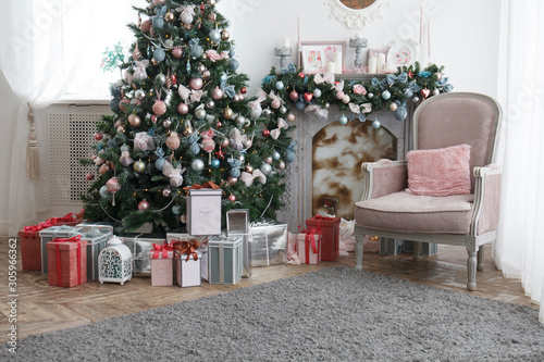 Christmas, xmas, New Year interior with pink and turquoise fur-tree decoration with balls and bowknots, ribbons, gift boxes, fireplace and armchair