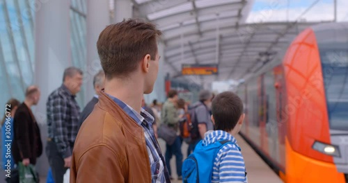 The platform of the ground station of the metro is full of passengers and the train is just arriving