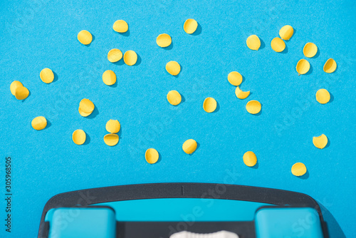 top view of holepunch with paper circles on blue background