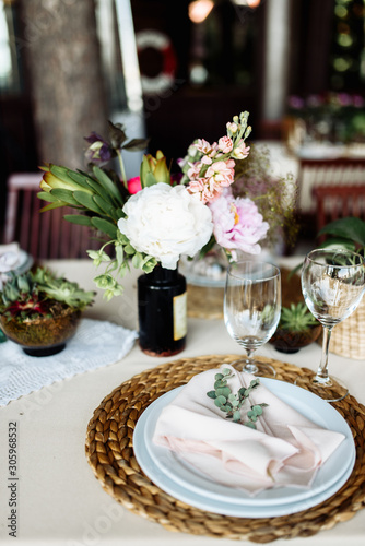 Festive table. A plate on a straw stand, a pink fabric napkin and a eucalyptus branch on it