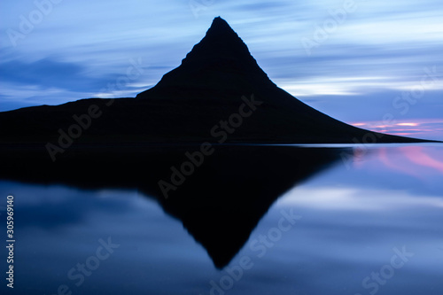 Tall steep mountain reflection in the water, black silhouette by the sunset, Iceland Kirkjufell