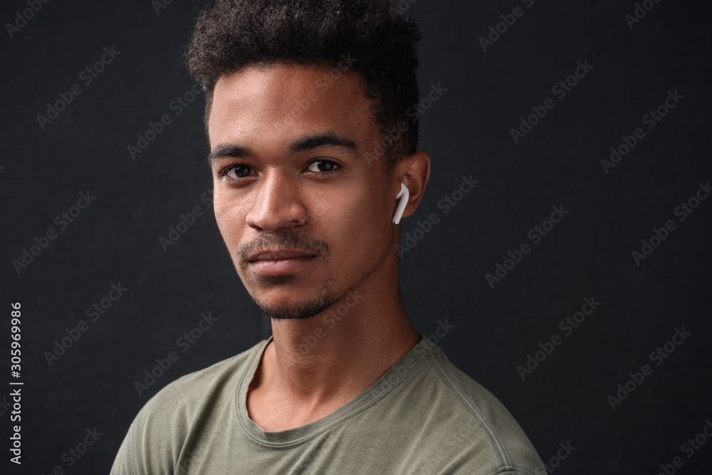 Photo of african american man looking at camera and using earpod Photo of african american man looking at camera and using earpod
