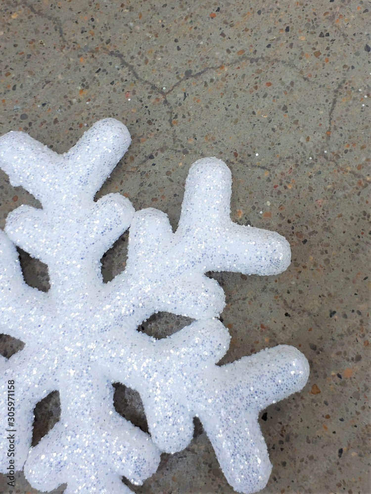 close-up of a white shiny vibrant snowflake on a gray concrete wall background close-up of a white shiny vibrant snowflake on a gray concrete wall background