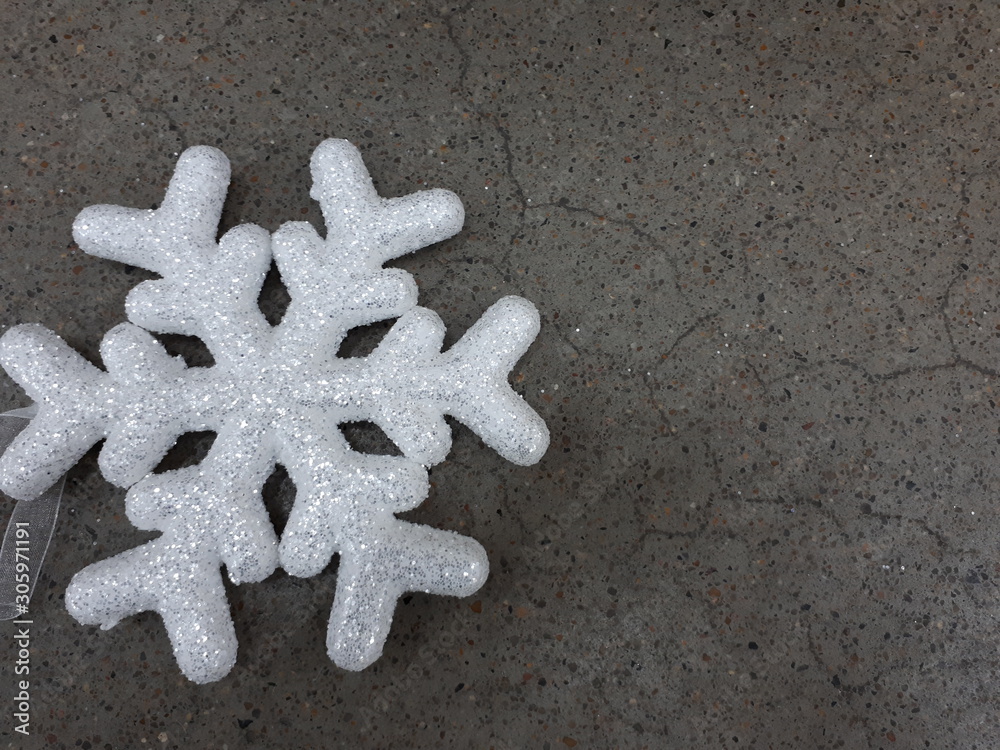 close-up of a white shiny vibrant snowflake on a gray concrete wall background close-up of a white shiny vibrant snowflake on a gray concrete wall background