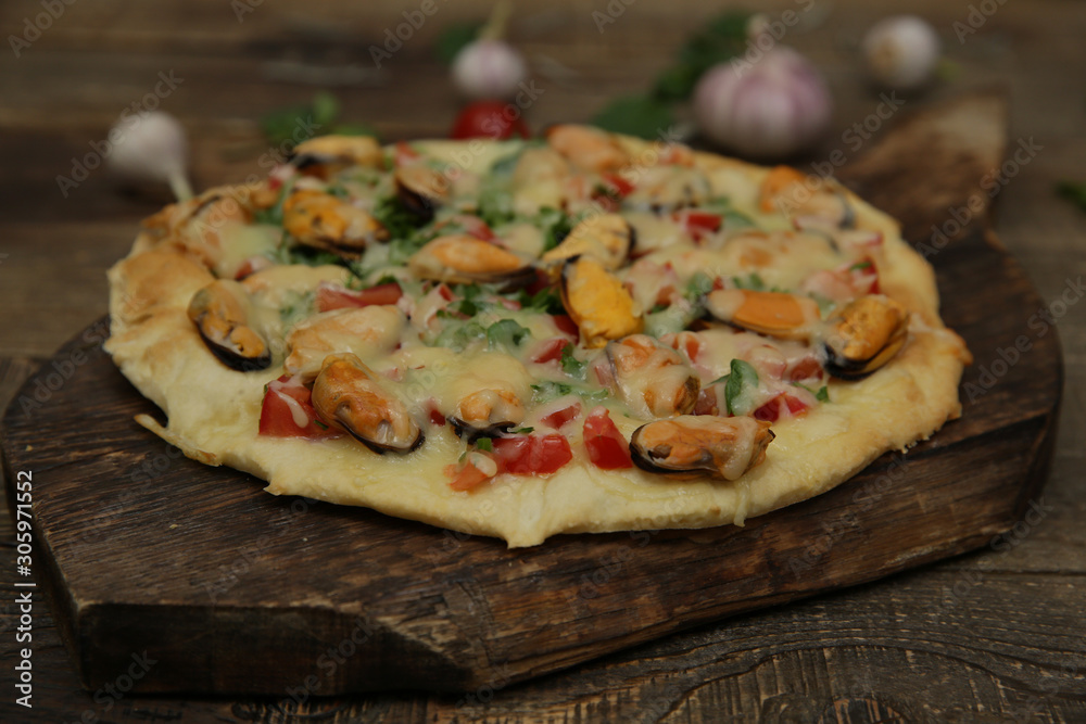 seafood pizza with mussels and mozzarella cheese isolated on a wooden board and on a wooden rustic table. Mediterranean food. Vegetarian. Close-up.