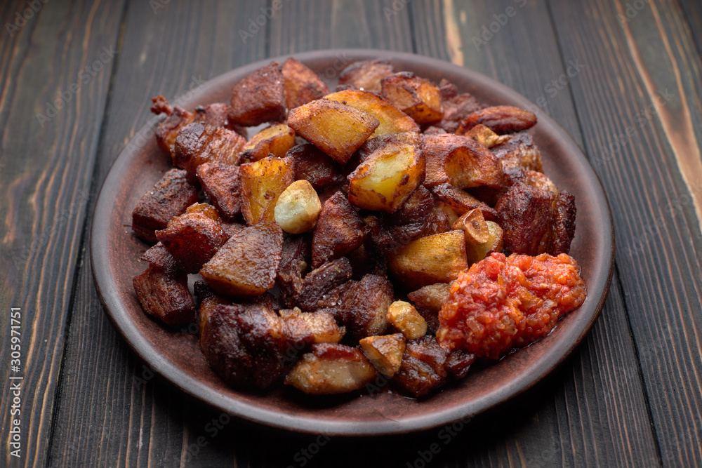 Homemade potato with meat, garlic, adjika, on wooden background