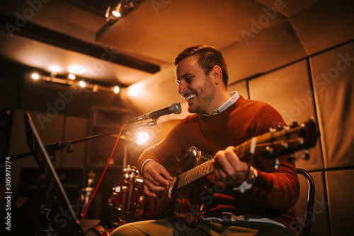 Portrait of a smiling musician singing and playing guitar