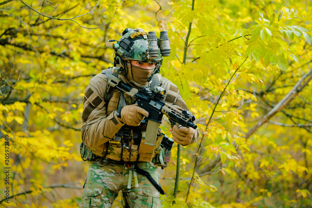 Airsoft man in uniform, move with machine gun on yellow forest backdrop