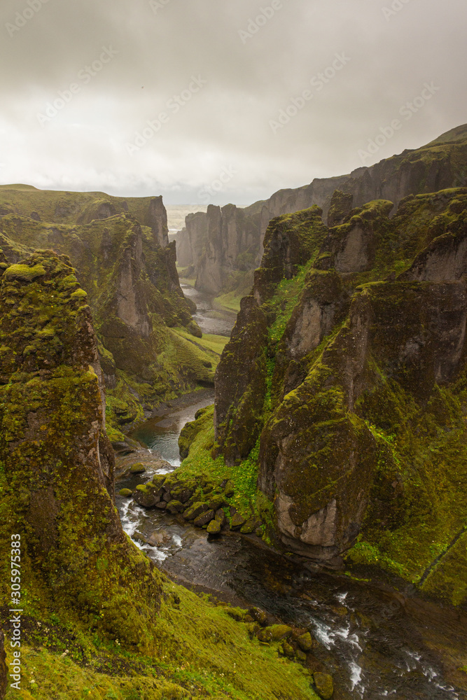 Deep dramatic canyon with narrow river, mossy stone, moss rock, Iceland Deep dramatic canyon with narrow river, mossy stone, moss rock, Iceland