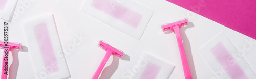 top view of disposable razors and wax depilation stripes on white and pink background, panoramic shot