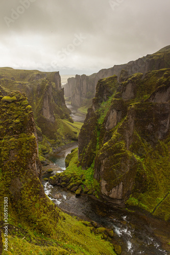 Deep dramatic canyon with narrow river, mossy stone, moss rock, Iceland
