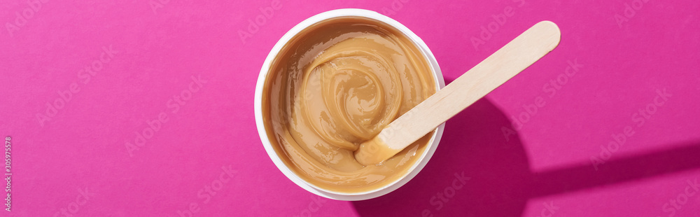 top view of depilation wax in cup with stick on pink background, panoramic shot - obrazy, fototapety, plakaty 