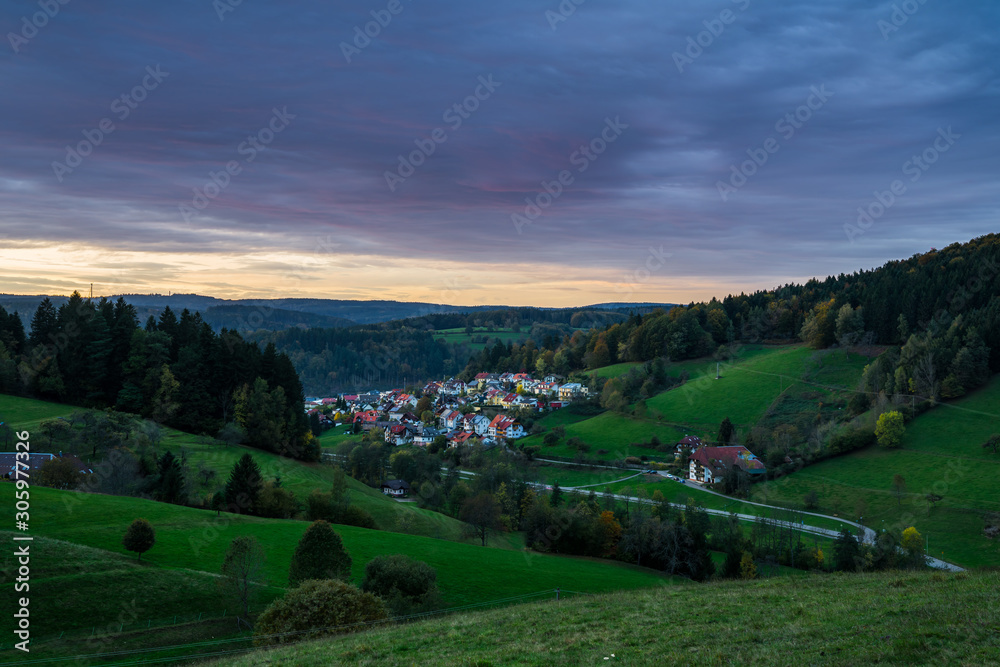 Germany, Idyllic black forest village elzach houses and streets in valley surrounded by fir trees at sunset, view above with red sky