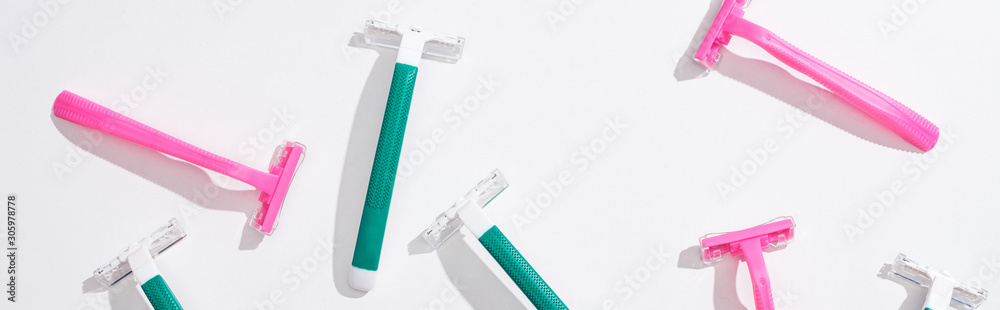 Fototapeta premium top view of female pink and green disposable razors on white background, panoramic shot