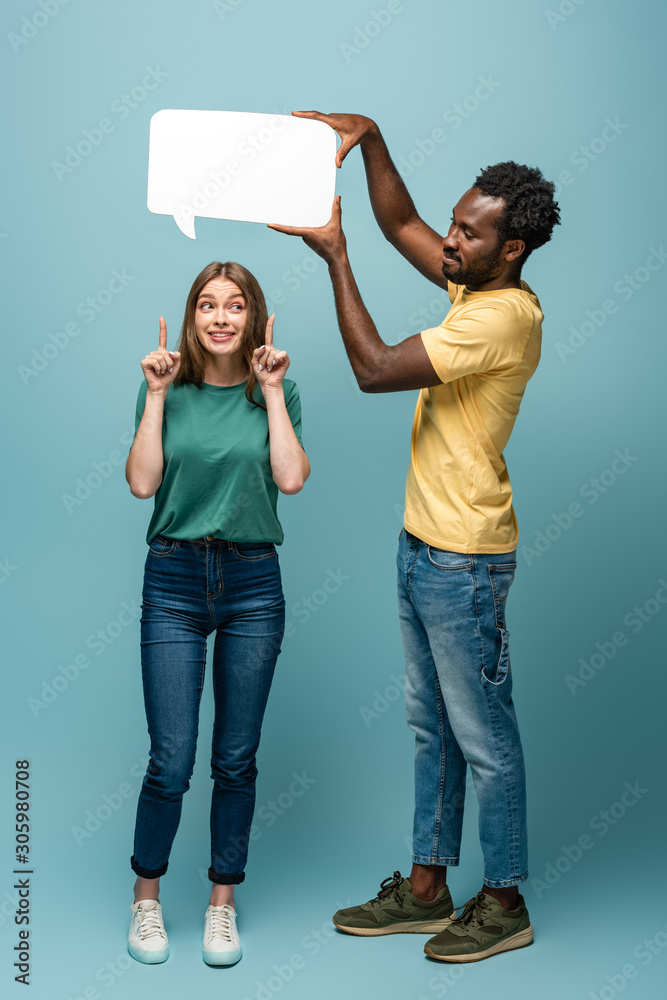 Obraz premium african american man holding speech bubble above girlfriend showing idea gesture on blue background