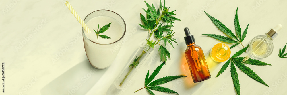 Cannabis milk, leaf of cannabis and a bottle of CBD Oil and tincture on the kitchen table. Top view, flat lay Banner - obrazy, fototapety, plakaty 