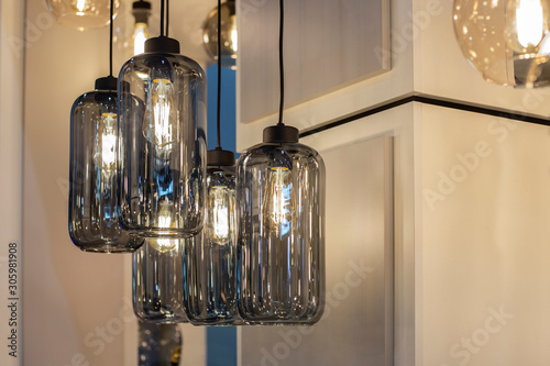 Pendant group of bottle shaped lighters made of dark grey transparent  glass with bulbs inside it. Trendy shandelier for contemporary loft interior