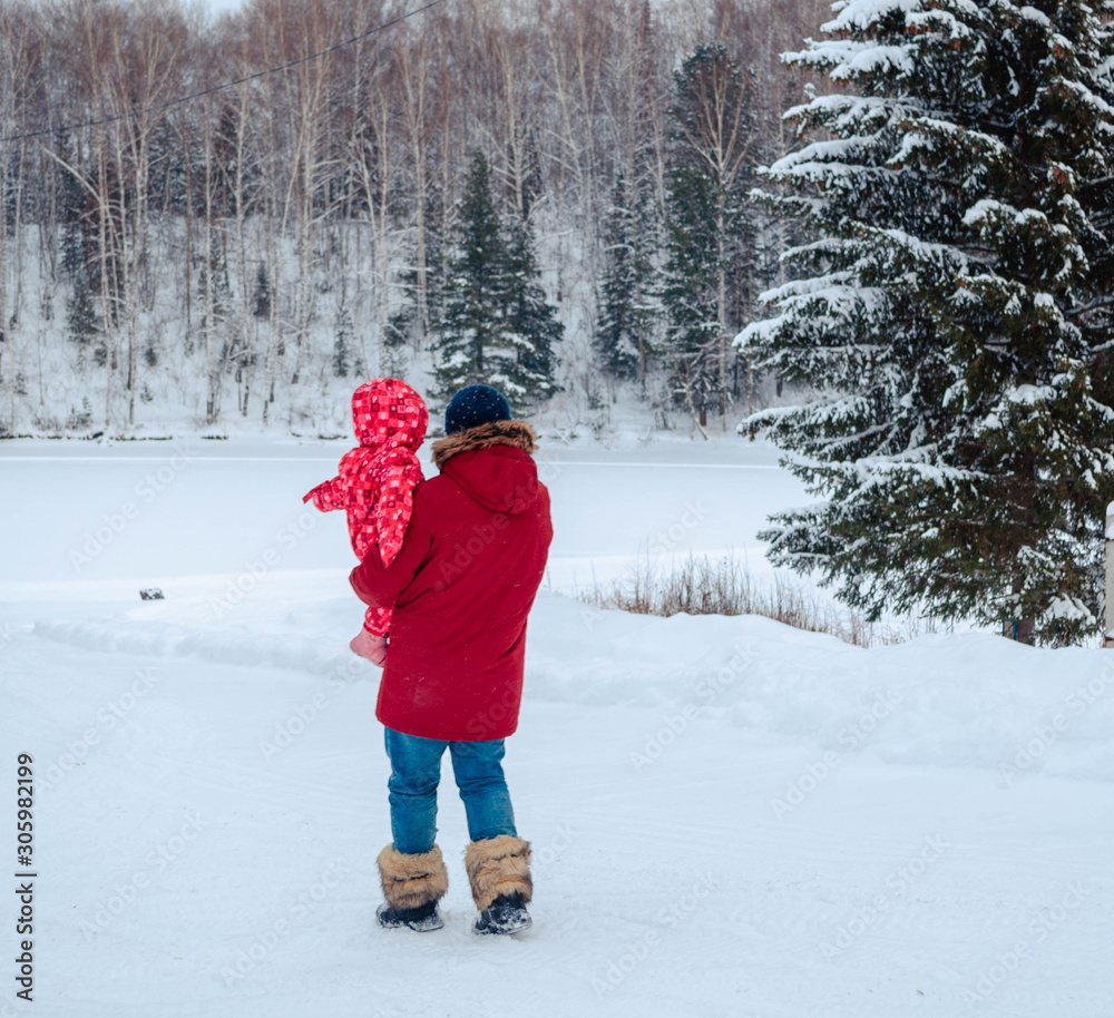 Asian dad and his little cute daughter in red have fun outdoors in winter. Walk through the winter snow-white forest. happy baby love family. New year and Christmas in Siberia.