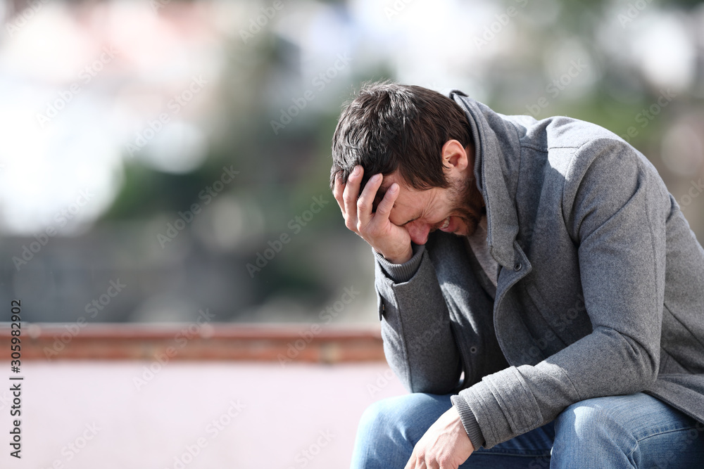 Worried man complaining sitting on a bench in winter Worried man complaining sitting on a bench in winter