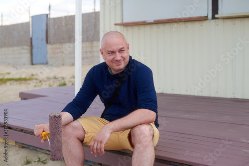 man on a painted porch with a roller in his hand photo