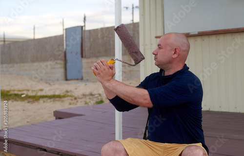 man on a painted porch with a roller in his hand photo